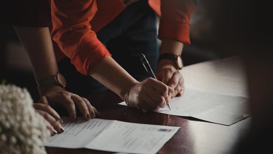 Dos personas rellenan un documento.